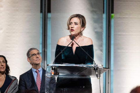 Debra Duardo delivers her McGraw Prize acceptance speech at a podium on stage in 2023 while representatives of Penn GSE watch behind her.